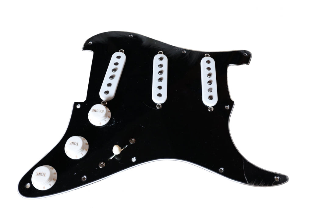 black Strat pick guard with white pickups on a sheep skin rug